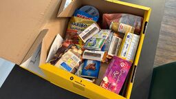 An open box filled with sweets, nuts, tea, a ginger shot and custom-labeled Twig bars.