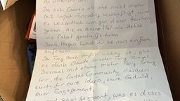 A handwritten German letter addressed to the core team lies on top of the snacks in the open care package.
