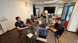 The Core Team sits with their laptops around a long table in a meeting room at the Unperfekthaus in Essen.